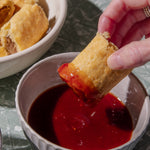 Person dipping a sausage roll into tomato sauce